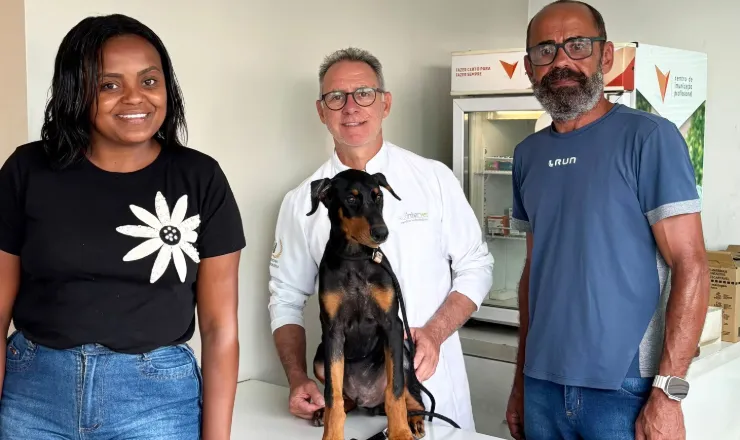 Veterinário da Intervet com um filhote de dobermann e os tutores